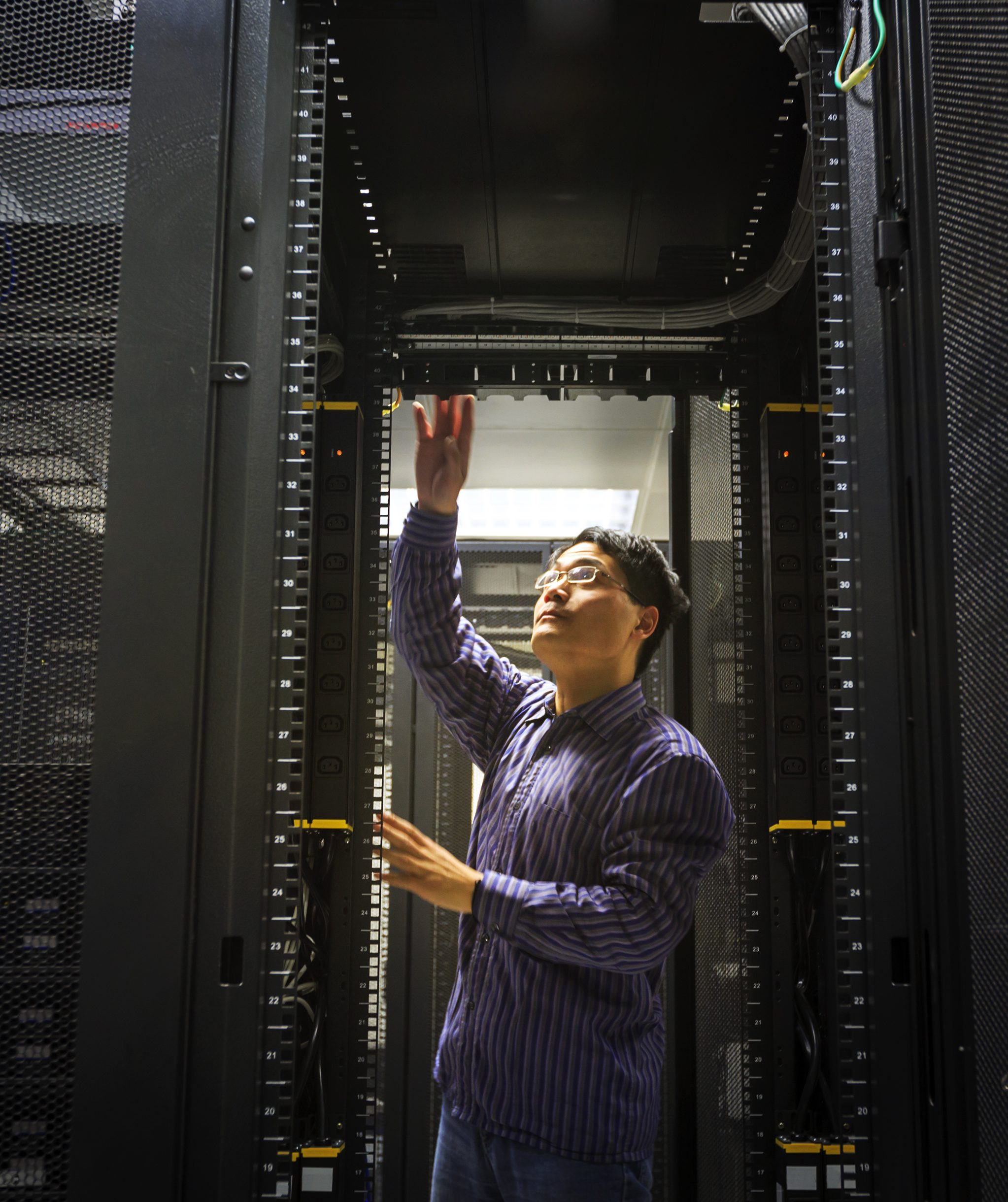 Technician performing network maintenance inside a server rack.