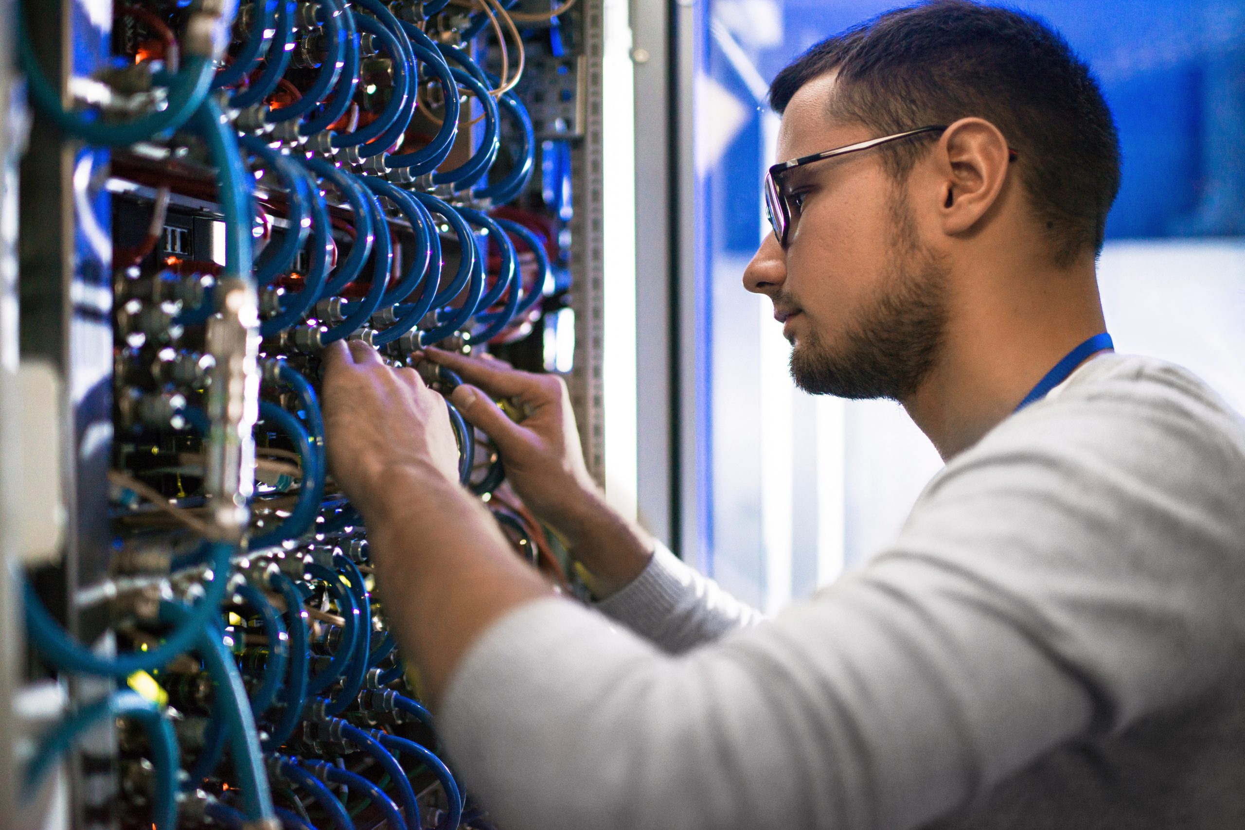 Close-up of engineer fastening hardware inside a server cabinet.